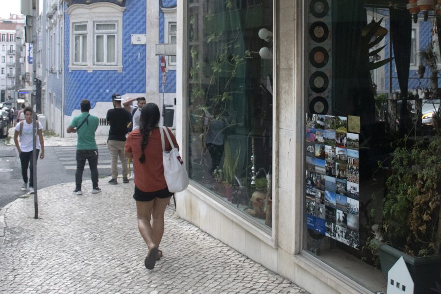 A street in Lisbon, Portugal. In one of the shop windows there is an exhibition of Shutter Hubs Postcards from Great Britain project, lots of postcard sized photographs