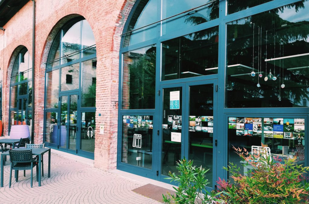 Photograph of the exterior of FuoriLuogo Asti with postcard-sized photographs displayed in the windows