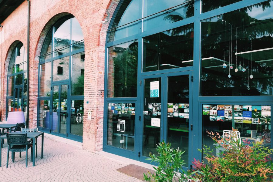 Photograph of the exterior of FuoriLuogo Asti with postcard-sized photographs displayed in the windows