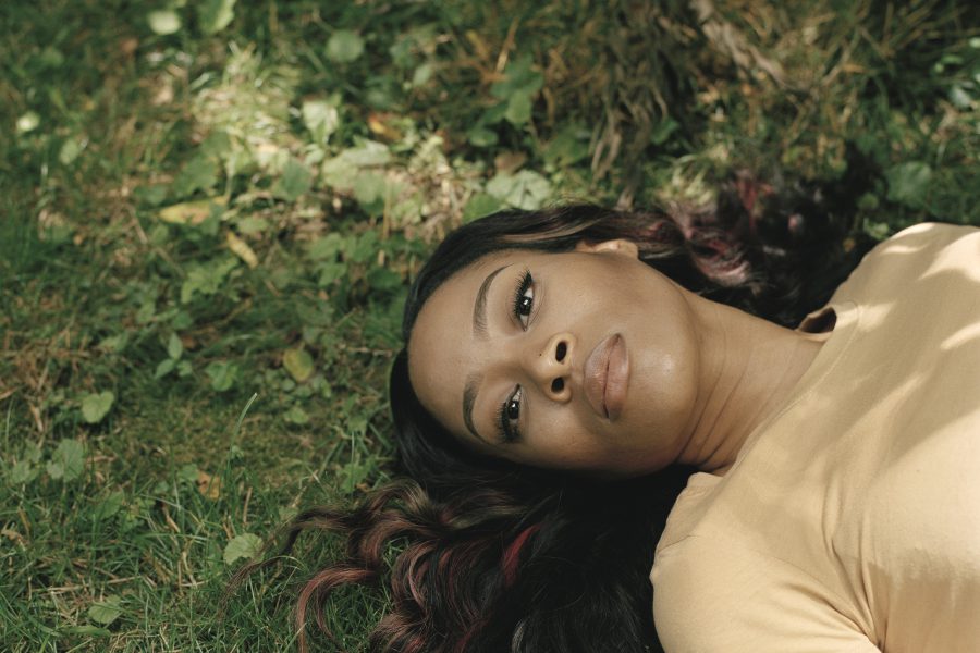 Photographic portrait of reclining women on green grass with dark hair and yellow blouse