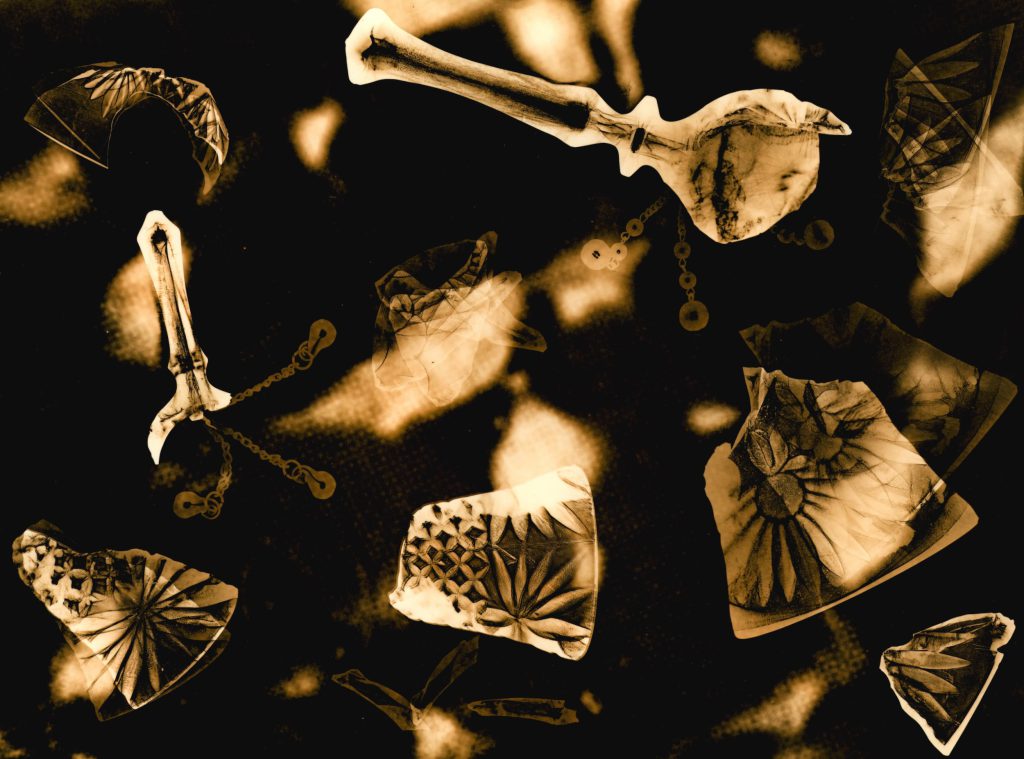 image of smashed crystal bells with pieces located across the image. The clappers from two of the bells are pictured in multiple positions to suggest movement. The background of the image contains a close up view of liver cells