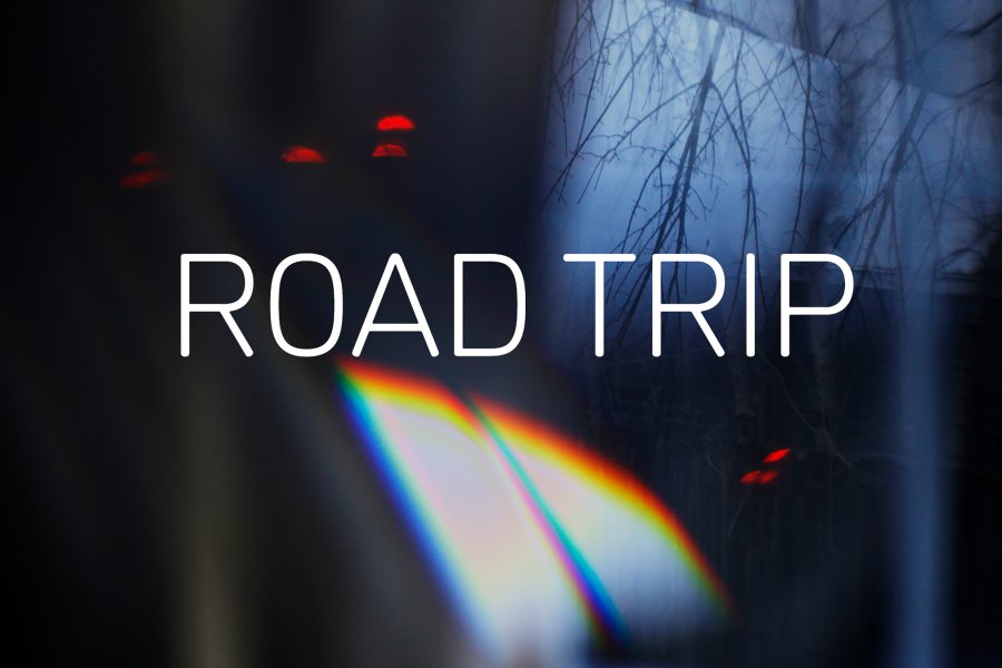 Graphic with a photograph showing reflections of lights and trees in the background and the text 'ROAD TRIP' in white in the centre