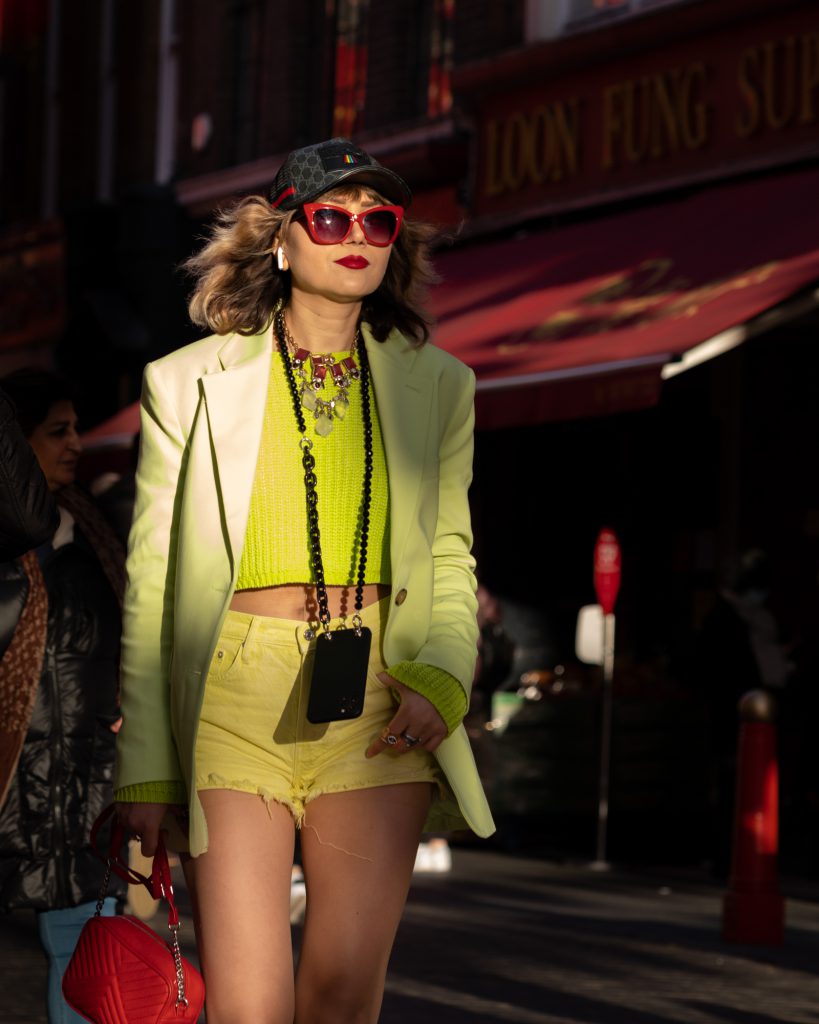Woman in street wearing yellow clothes lit by low winter sunlight