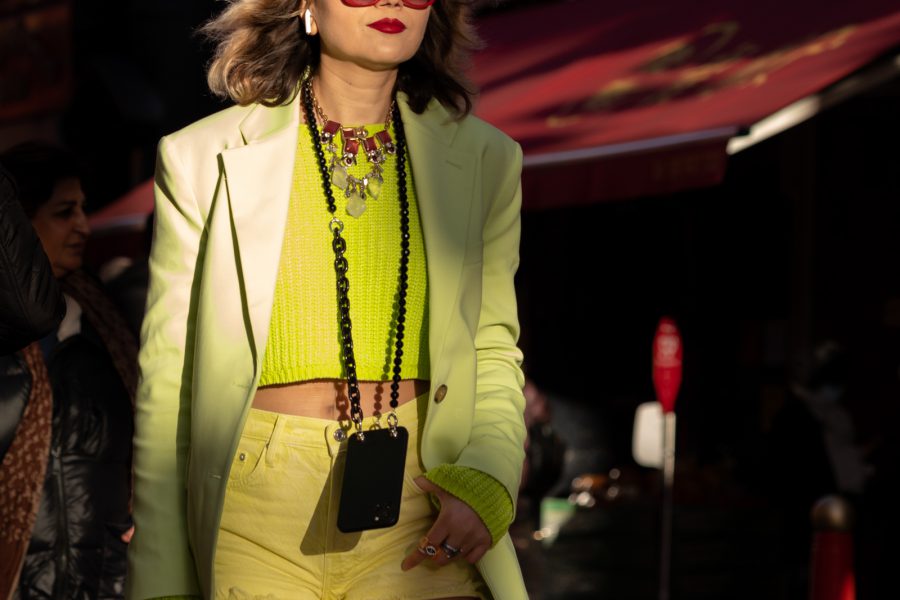 Woman in street wearing yellow clothes lit by low winter sunlight