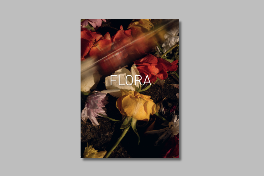 Book cover with multi-coloured floral bouquet in close-up. Text reads 'FLORA'. Seen on grey background.