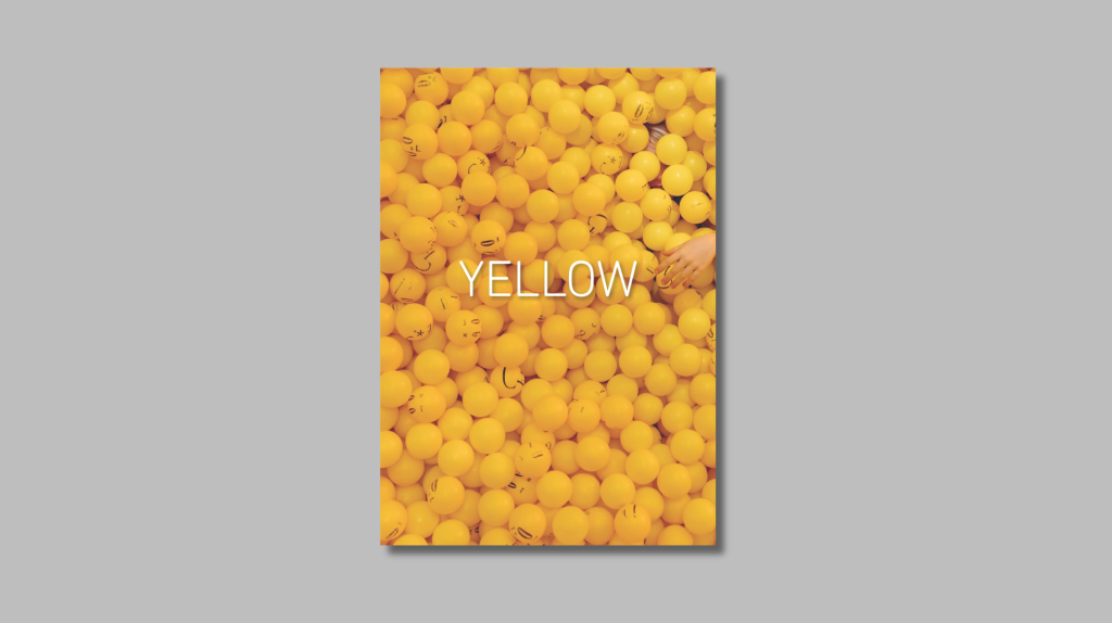 YELLOW photobook cover with image of ballpit filled with yellow plastic balls, and a hand reaches into the pit.